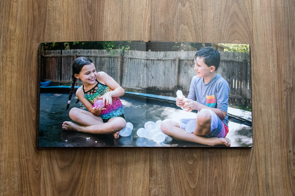 photo album opened to siblings with water balloons on a trampoline in Austin