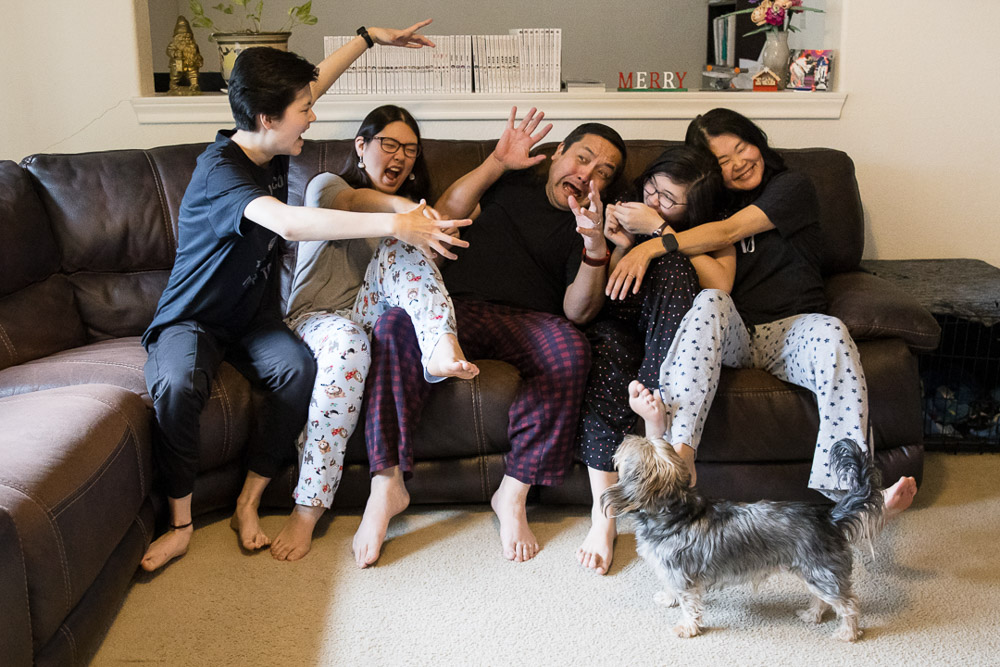 Family of 5 being silly in their pajamas with their dog looking at them