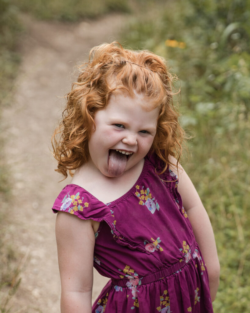 Redhead little girl sticking her tongue at family photo session in Austin, TX