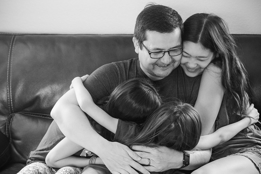 Austin Dad with 3 girls hugging him on a couch.
