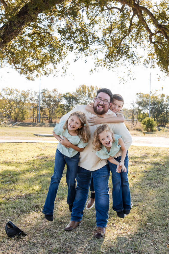 Father laughing with his children during a playful outdoor lifestyle family photography session in Austin, Texas.