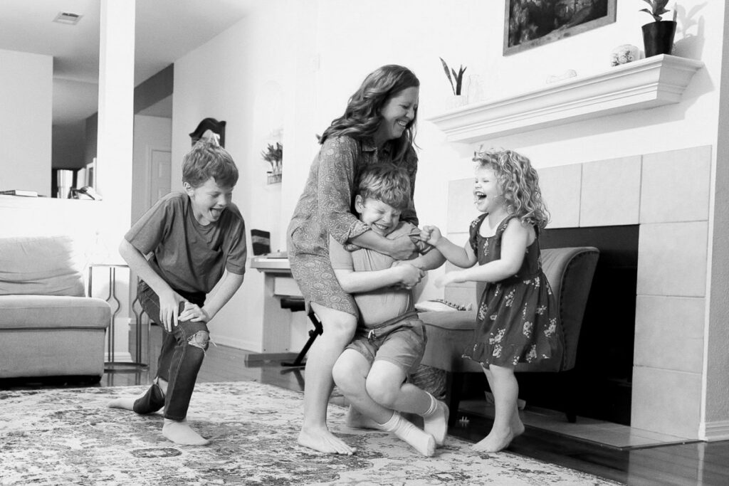 Mother having a dance party with her children at home during a candid in-home lifestyle family photography session in Austin.