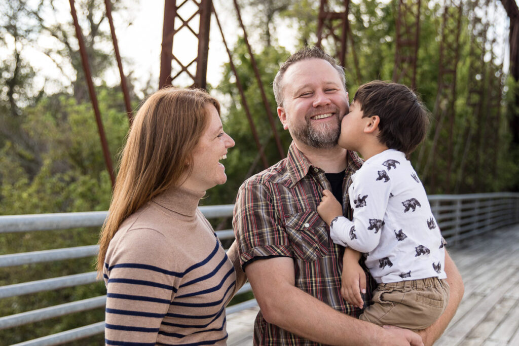 Parents smiling and connecting with their child outdoors during a lifestyle family photography session in Austin, Texas.