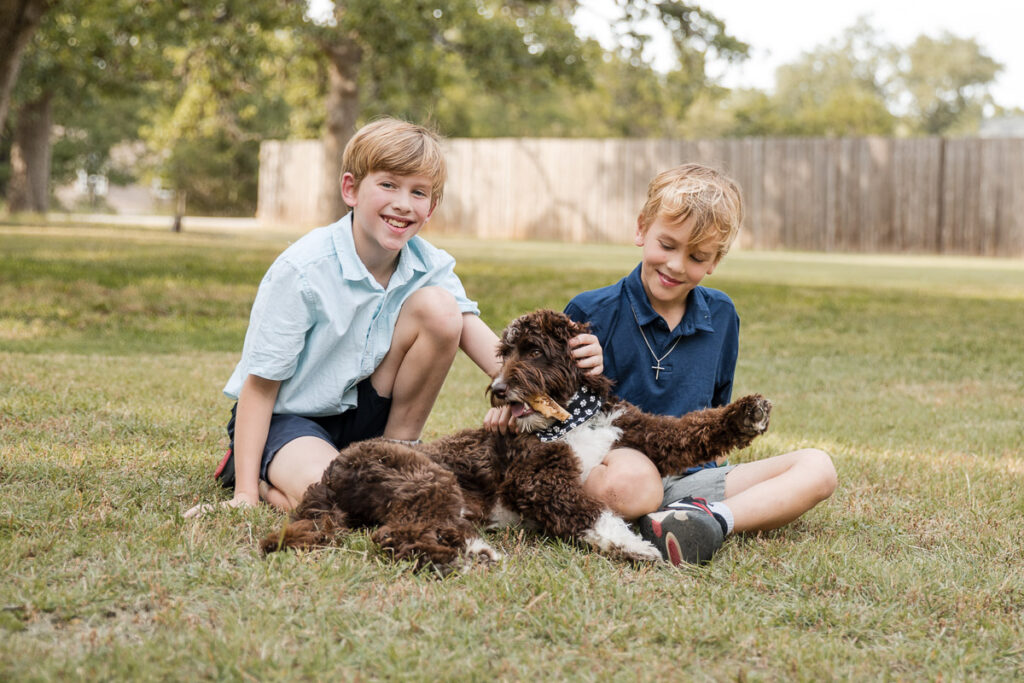 Children playing with their dog in the backyard during a candid lifestyle family photography session.