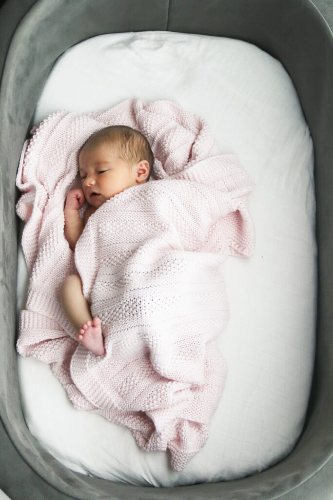Newborn wrapped in blanket in bassinet during lifestyle newborn photography in Austin home