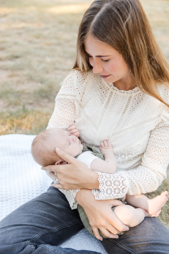 Mother cuddling newborn baby during relaxed out-door newborn session in Austin TX