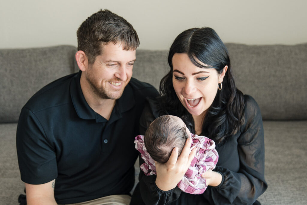 New parents smiling at their newborn during in-home newborn photography in Austin