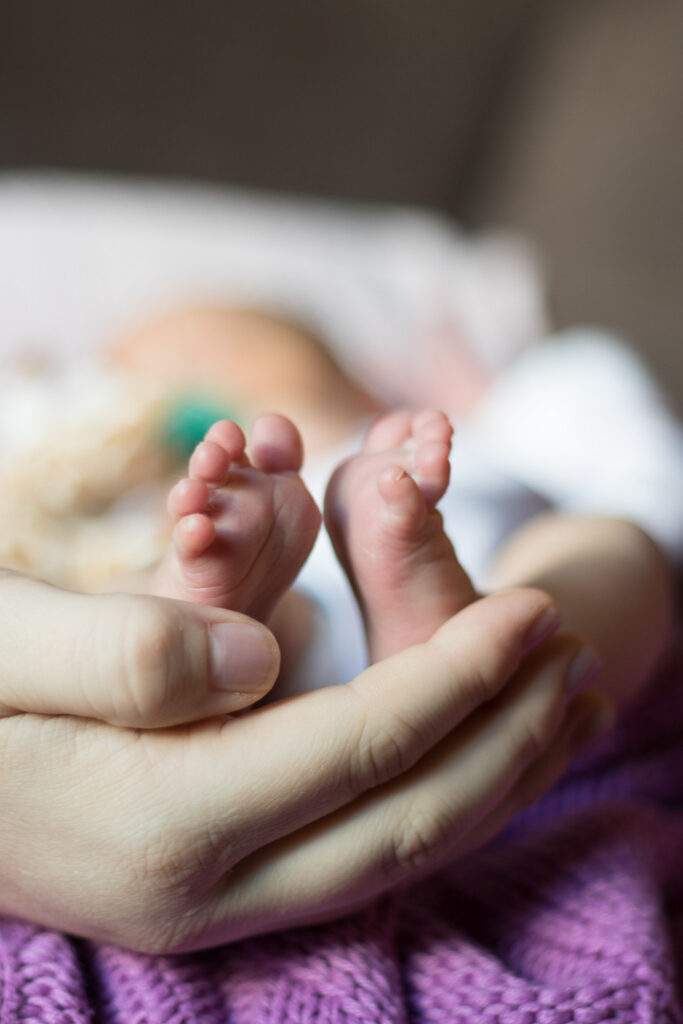 Detail photo of parent holding newborn feet during in-home newborn photography in Austin