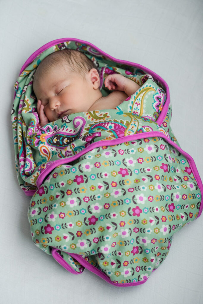 Swaddled newborn sleeping during lifestyle in-home newborn photography in Austin