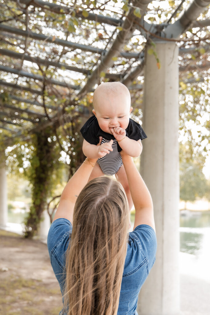 Austin mom with smiling baby in the air.
