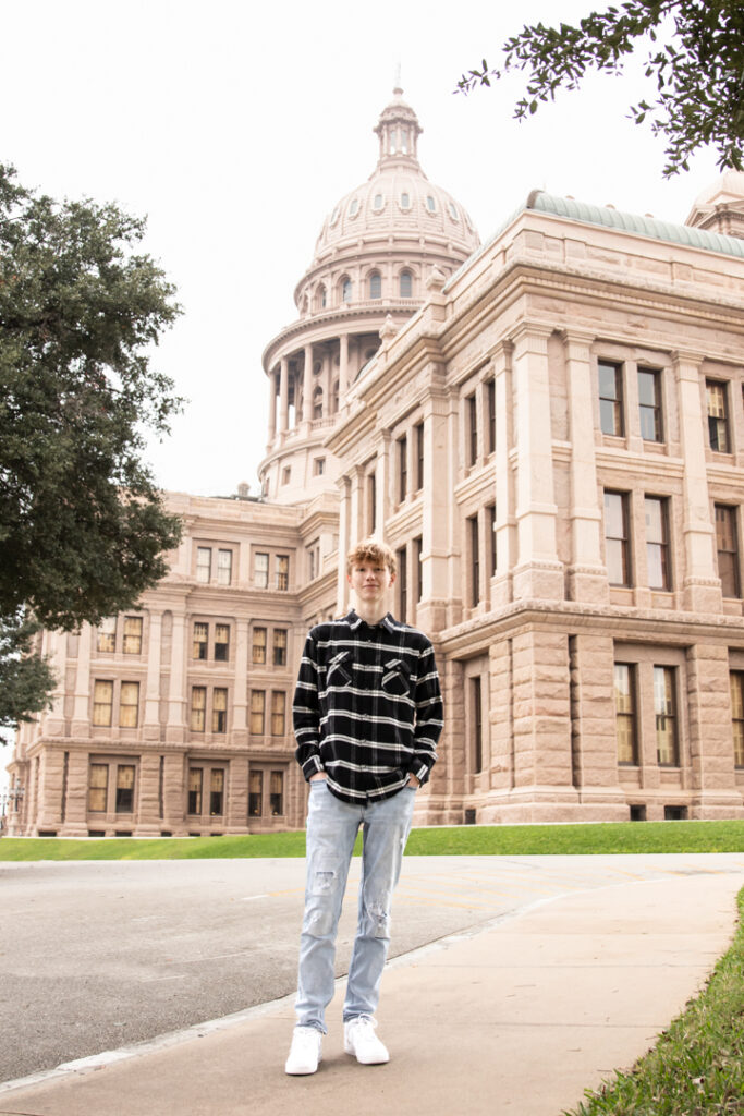 Teen boy in front of the Texas State Capitol building during his Austin senior photography session.