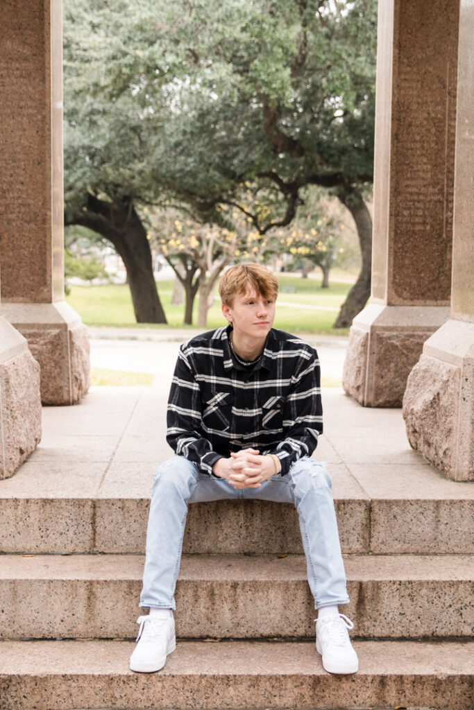 Teen boy sitting on the steps of the Texas State Capitol during his Austin senior portrait session.