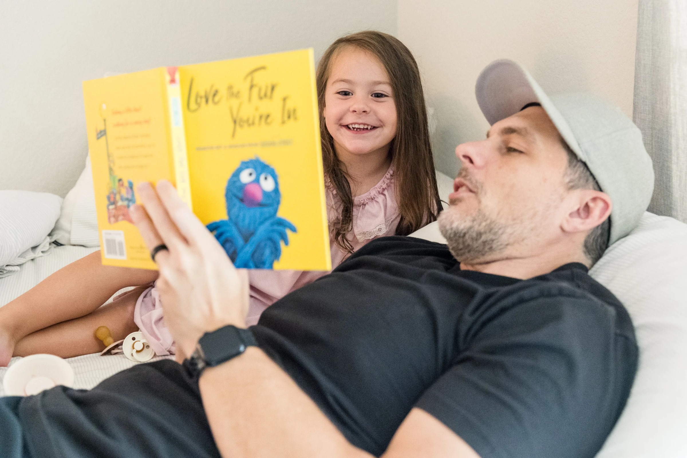 Parent and child reading a children's book together on a bed during a family session in Austin, TX