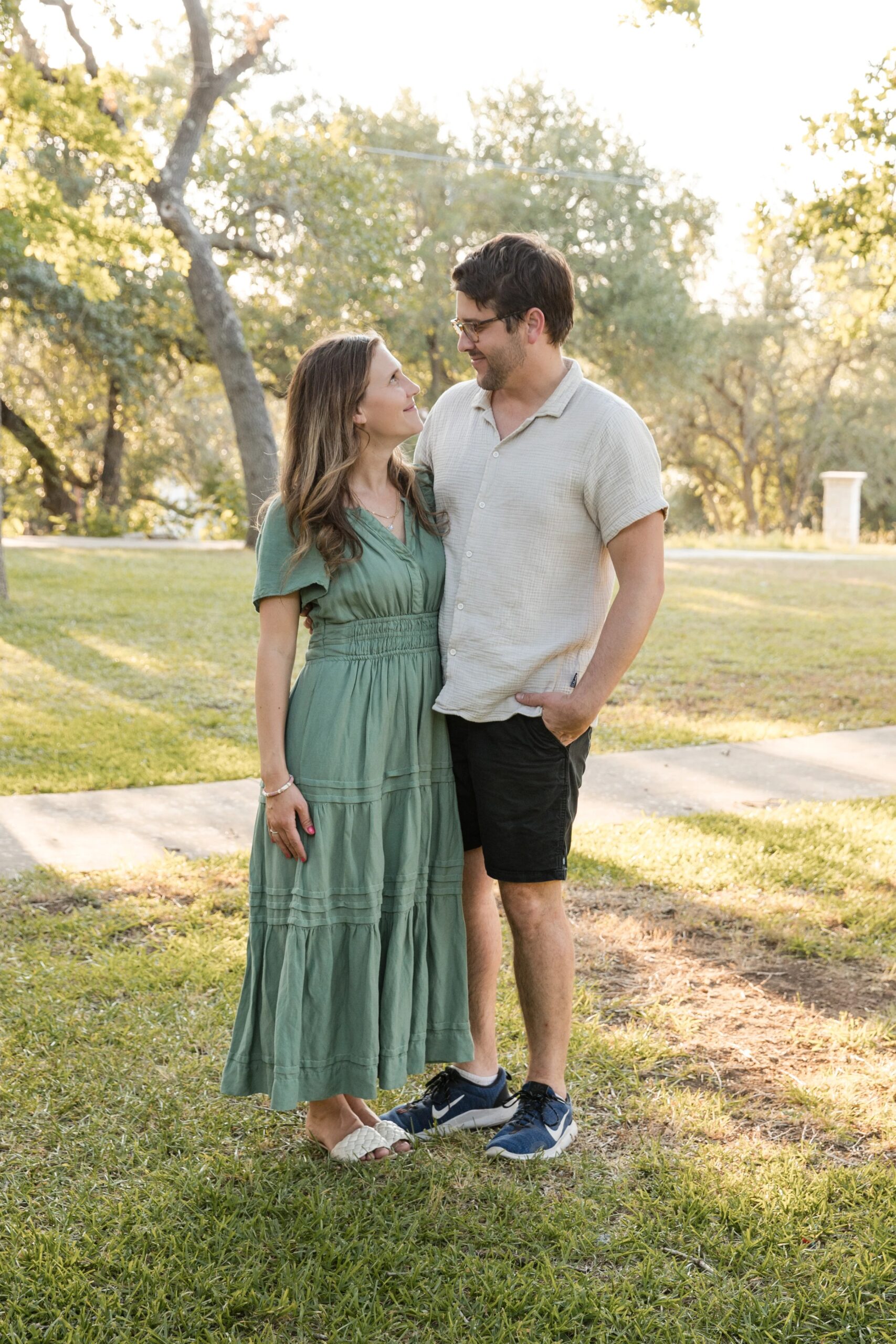 Couple stands close together outdoors during golden hour in a park, part of a family photography session in Austin, TX