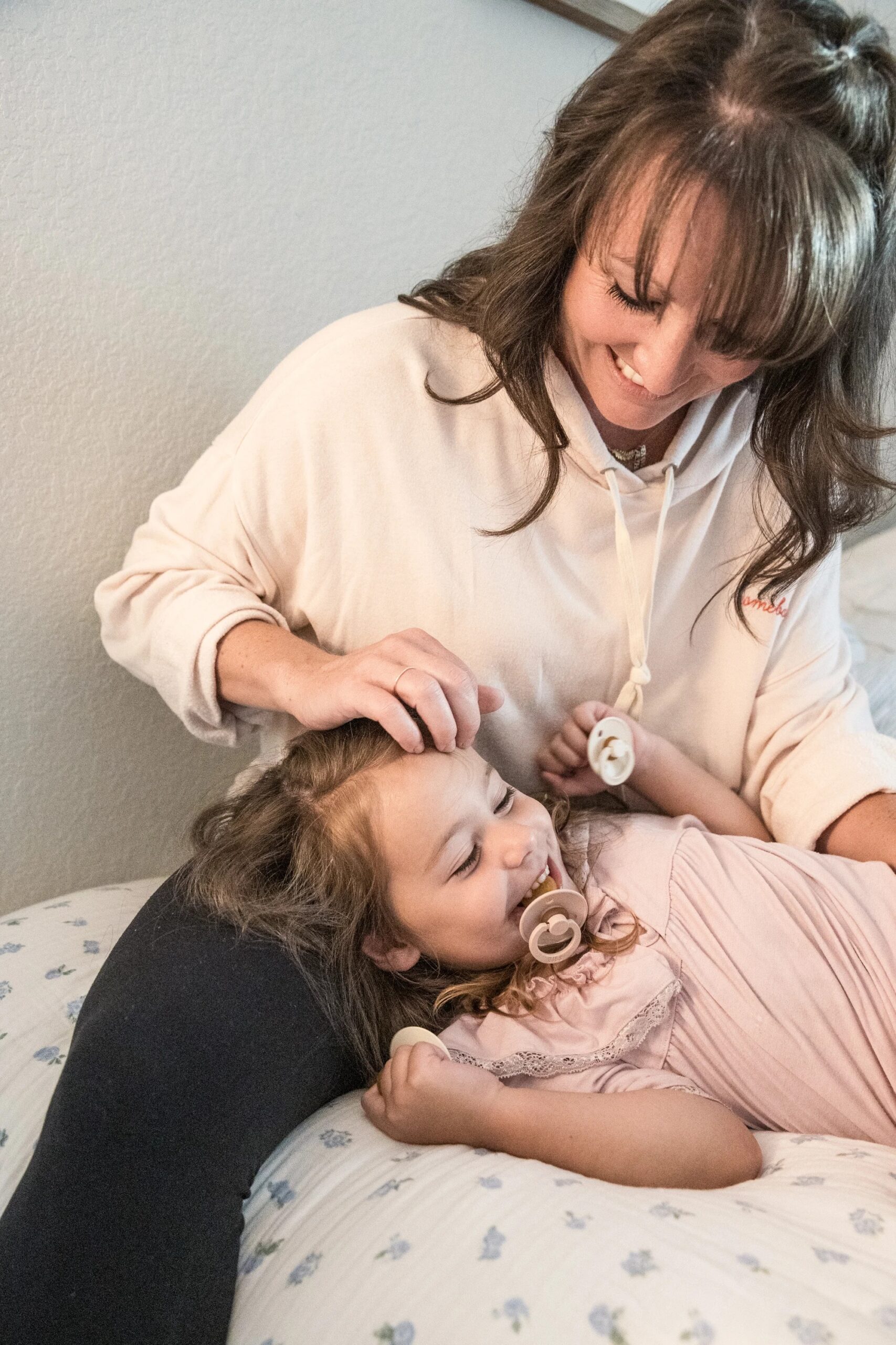 Woman smiling with daughter laying on her lap during a family photography session in Austin, TX