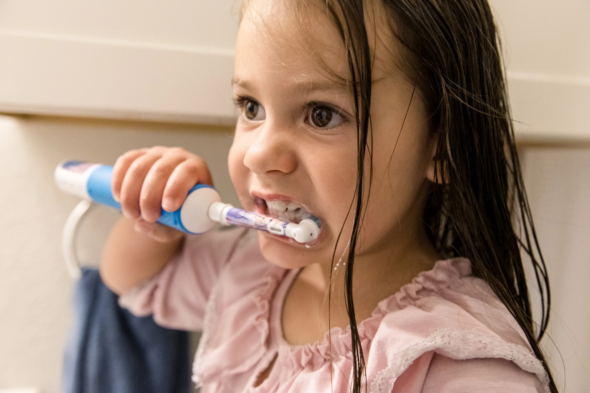 Young child brushing teeth with an electric toothbrush in a family photography session at an Austin, TX home